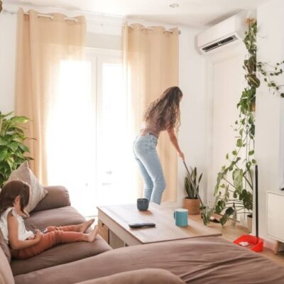W salonie z roślinami, dużą sofą i telewizorem zamontowana jest klimatyzacja do domu.