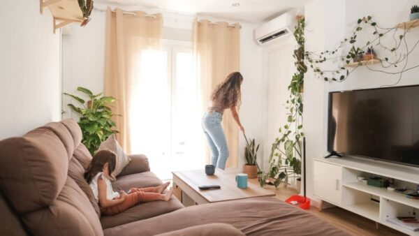 W salonie z roślinami, dużą sofą i telewizorem zamontowana jest klimatyzacja do domu.