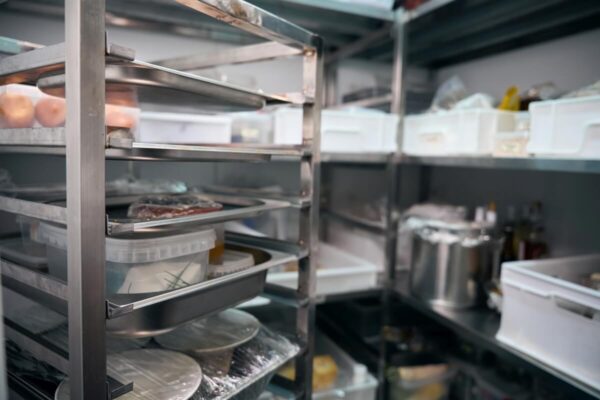 Wnętrze komory chłodniczej z półkami pełnymi żywności.