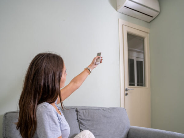 Osoba włącza klimatyzację do mieszkania za pomocą pilota.