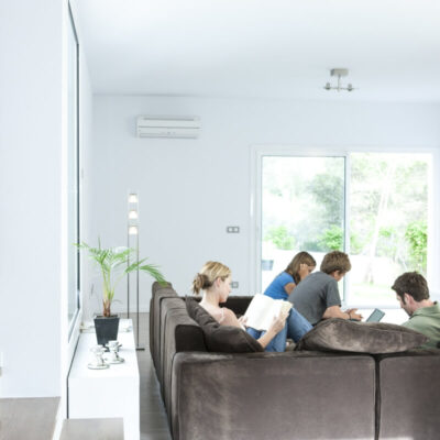 W nowoczesnym salonie, gdzie grupa młodych ludzi odpoczywa na kanapie, zainstalowana jest klimatyzacja do mieszkania.