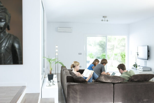 W nowoczesnym salonie, gdzie grupa młodych ludzi odpoczywa na kanapie, zainstalowana jest klimatyzacja do mieszkania.