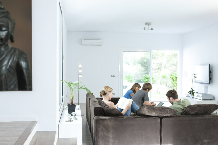 W nowoczesnym salonie, gdzie grupa młodych ludzi odpoczywa na kanapie, zainstalowana jest klimatyzacja do mieszkania.