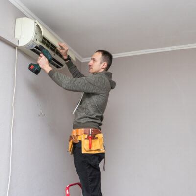 Mężczyzna wykonuje montaż klimatyzacji na ścianie.