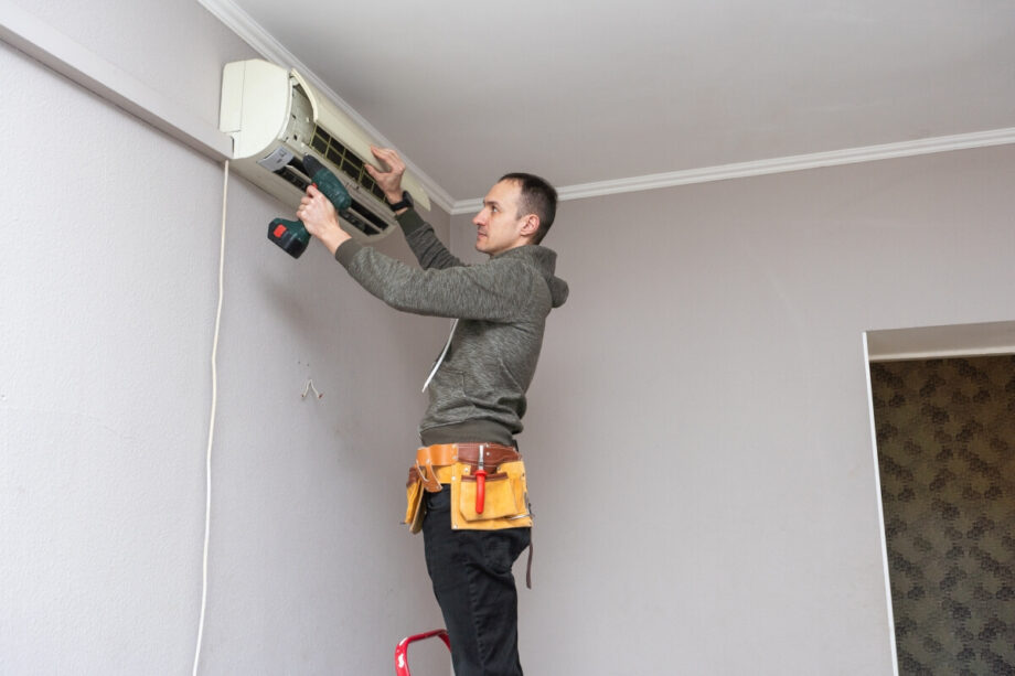 Mężczyzna wykonuje montaż klimatyzacji na ścianie.