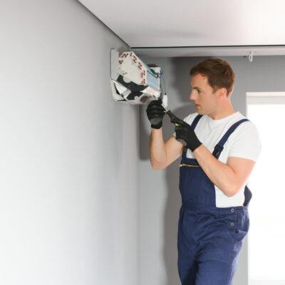 Mężczyzna wykonuje montaż klimatyzacji na ścianie.