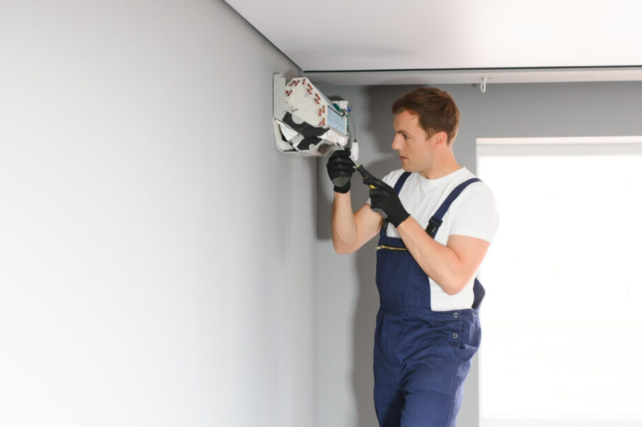 Mężczyzna wykonuje montaż klimatyzacji na ścianie.