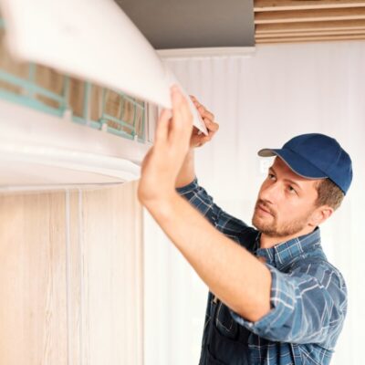 Pracownik w trakcie montażu klimatyzacji na ścianie.