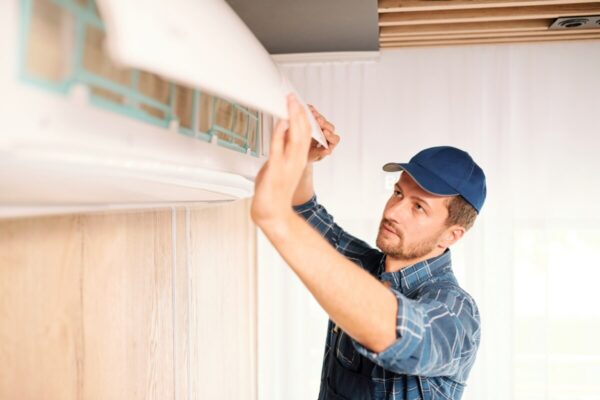 Pracownik w trakcie montażu klimatyzacji na ścianie.