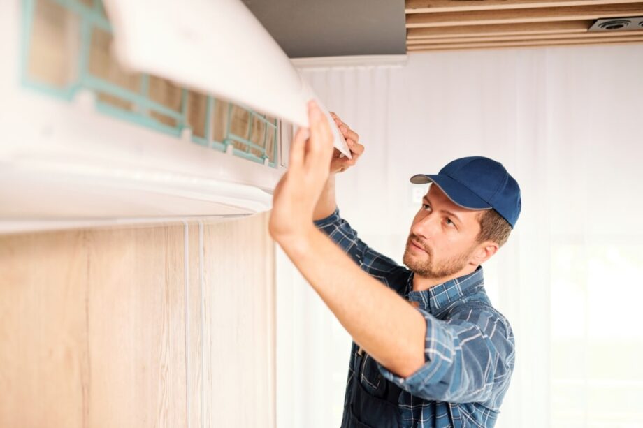 Pracownik w trakcie montażu klimatyzacji na ścianie.