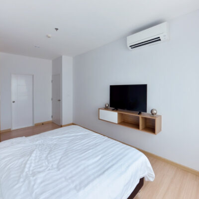 Nowoczesna sypialnia z telewizorem na ścianie i klimatyzacją do domu.