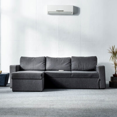 Nowoczesny salon z szarą sofą i klimatyzacją do domu na ścianie.