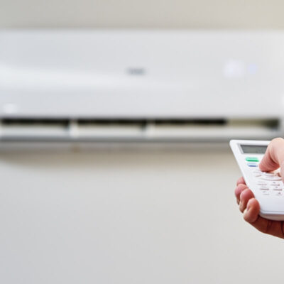 Osoba używająca pilota do regulacji klimatyzacji do mieszkania.