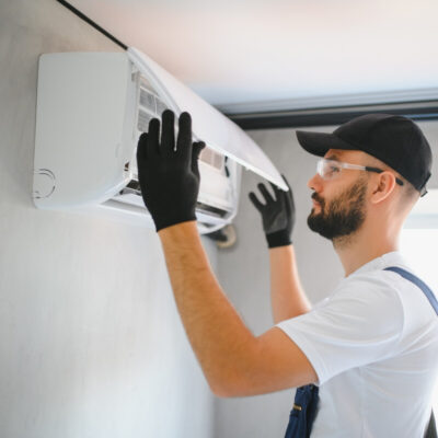 Mężczyzna przeprowadza montaż klimatyzacji na ścianie.