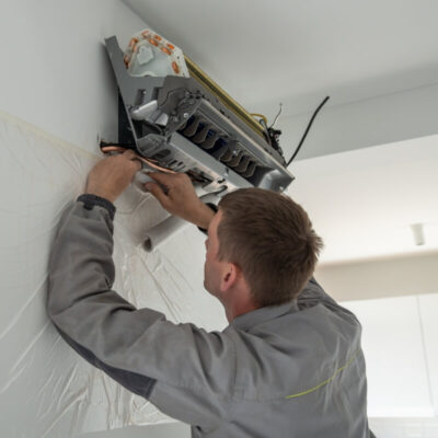 Technik przeprowadza montaż klimatyzacji w pomieszczeniu.
