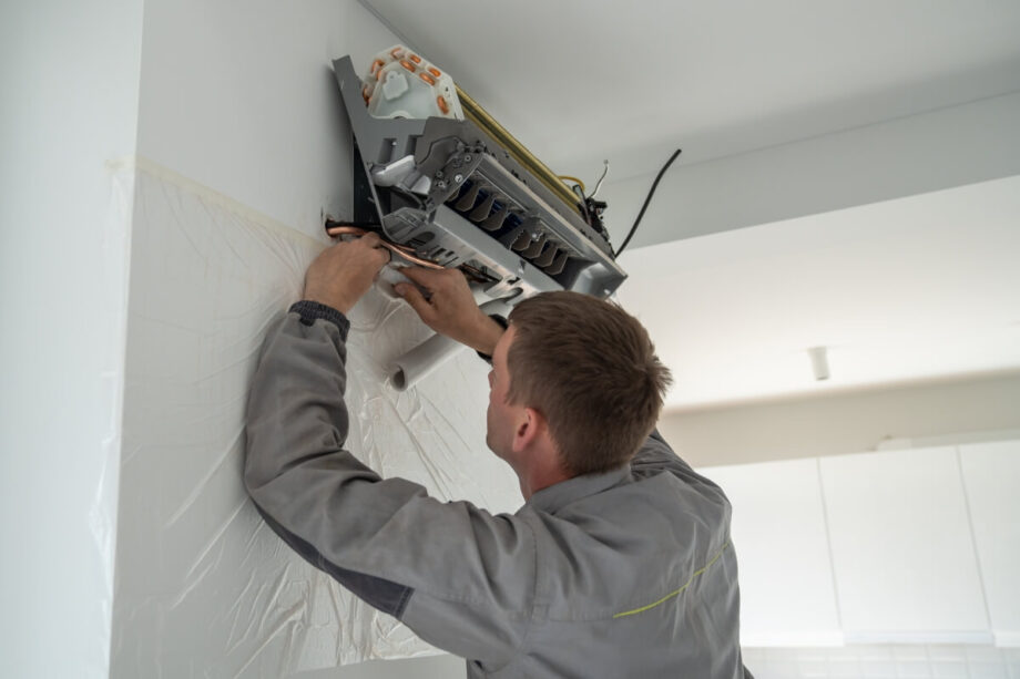 Technik przeprowadza montaż klimatyzacji w pomieszczeniu.